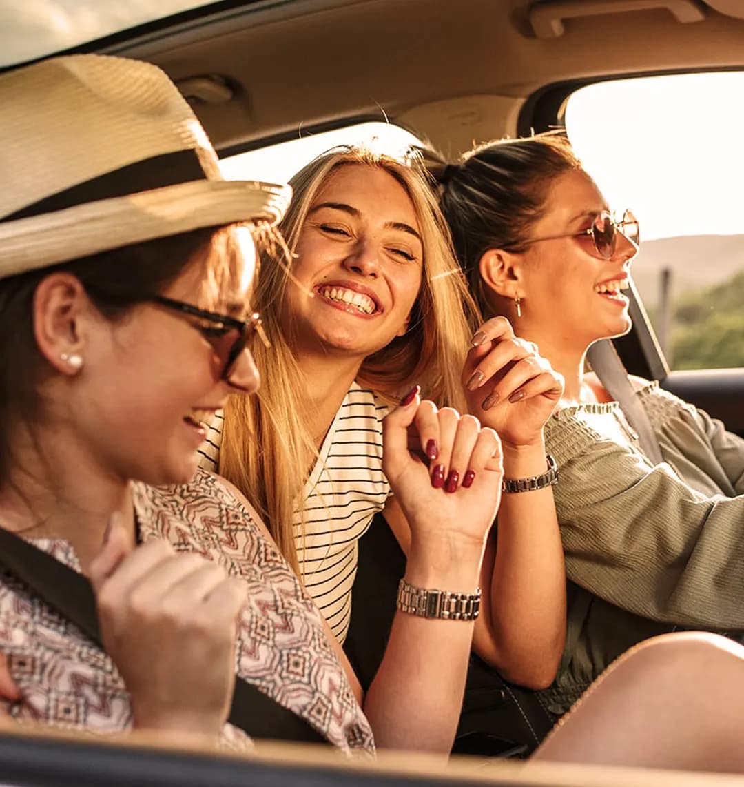 3 Freundinnen sitzen gemeinsam im Auto und lachen