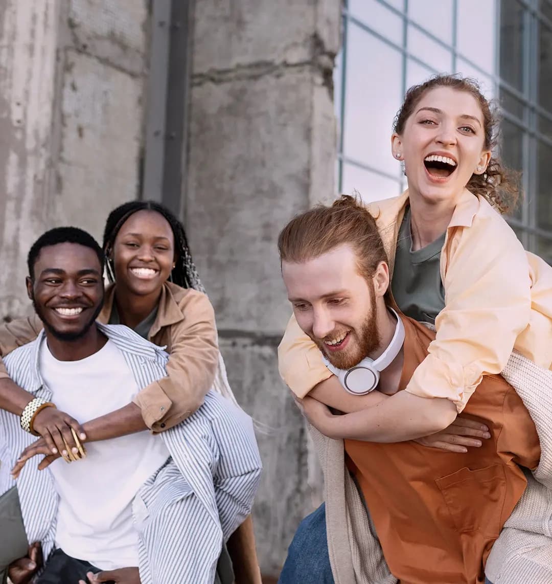Zwei junge Männer und zwei junge Frauen sind in der Stadt unterwegs. Sie haben Spaß und lachen.
